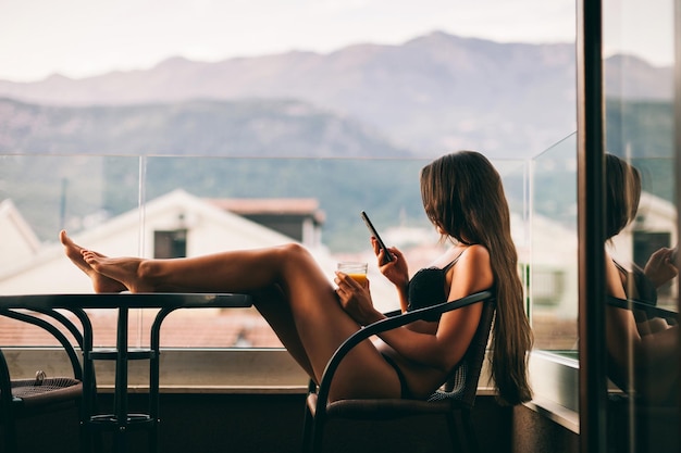 young woman in lingerie using smart phone on balcony