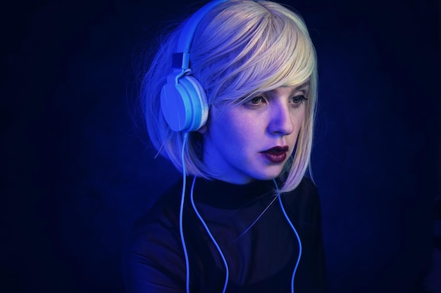 Young woman listening music against black background