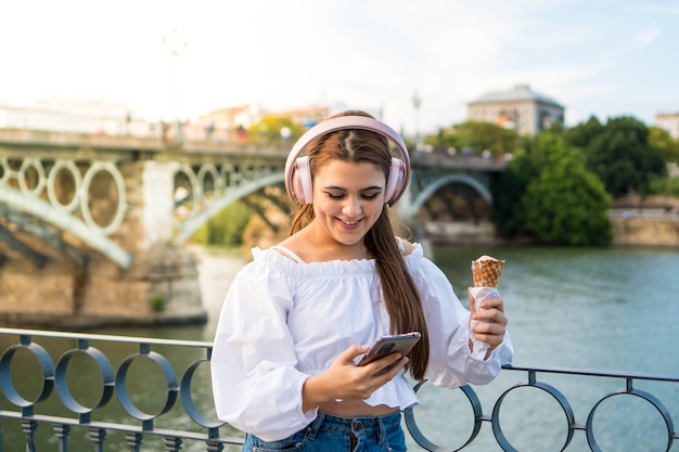 音楽を聴いて、夏に屋外でアイスクリームを食べる若い女性