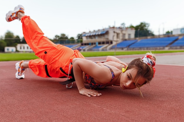 Young woman listening to music and exercising on stadium