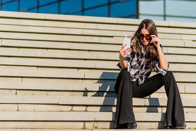 Young woman listening music from phone outdoor