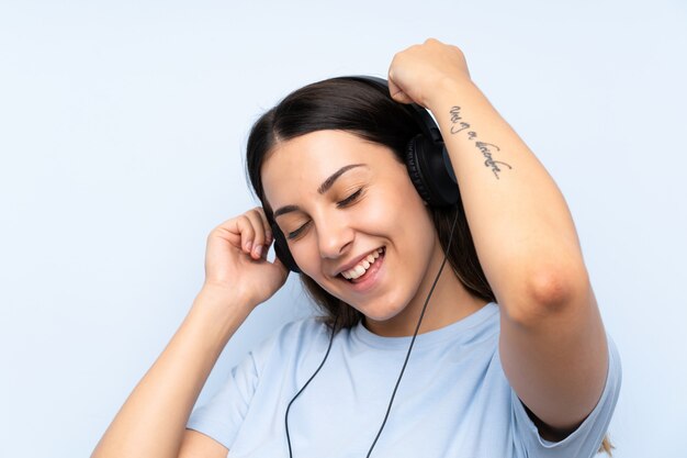 Young woman listening music over isolated blue background