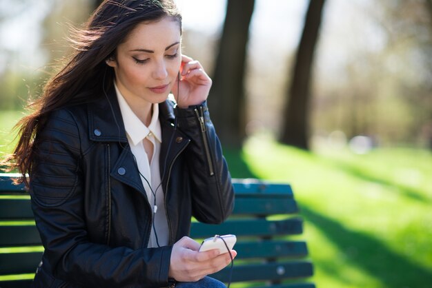 Young woman listening music in a park