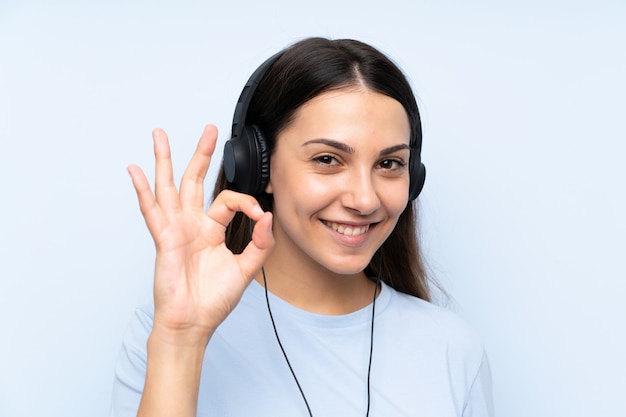 Young woman listening music showing ok sign with fingers