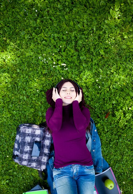 Young Woman to Listening Music via Headphone in the Park. top view