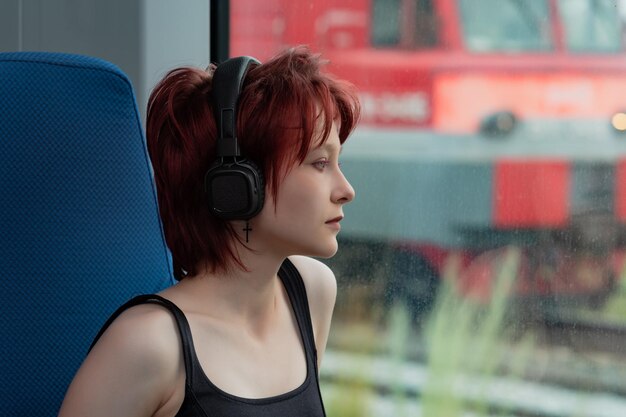 Young woman listening to music while riding in a commuter train car