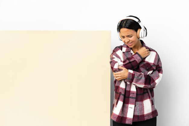 Young woman listening music with a big empty placard over isolated background with pain in elbow