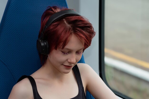 高速列車に乗りながらヘッドフォンで音楽を聴く若い女性