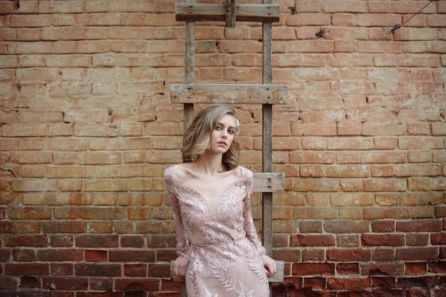 Young woman in a long pink dress with lace posing on the street