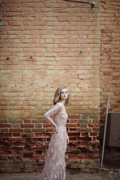 Young woman in a long pink dress with lace posing on the street