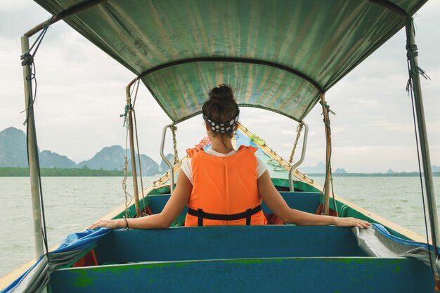 Young woman on the long-tail boat during her vacations in Thailand