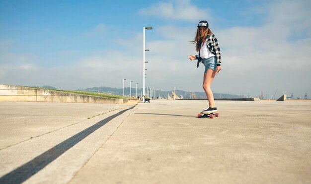 ビーチの遊歩道でロングボードをする若い女性