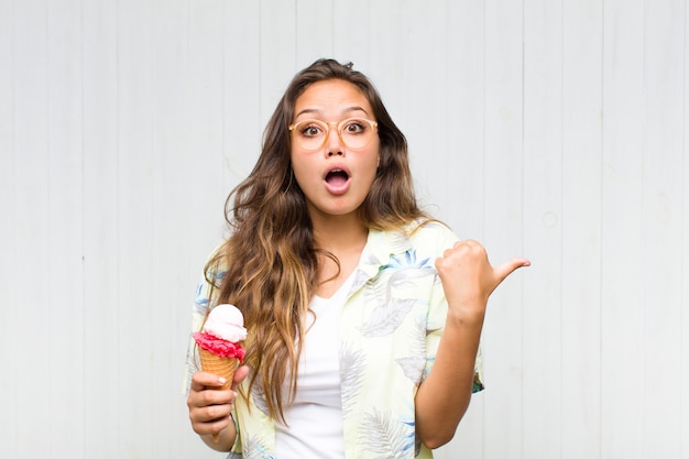 Young woman looking astonished in disbelief, pointing at object on the side