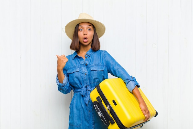 Young woman looking astonished in disbelief, pointing at object on the side