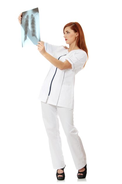 Фото Молодая женщина смотрит на медицинский рентген, стоя на белом фоне