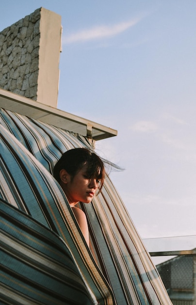 Photo young woman looking away amidst curtains against sky