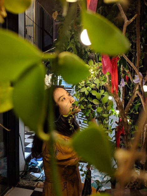 Foto giovane donna che guarda via vista attraverso le piante all'aperto