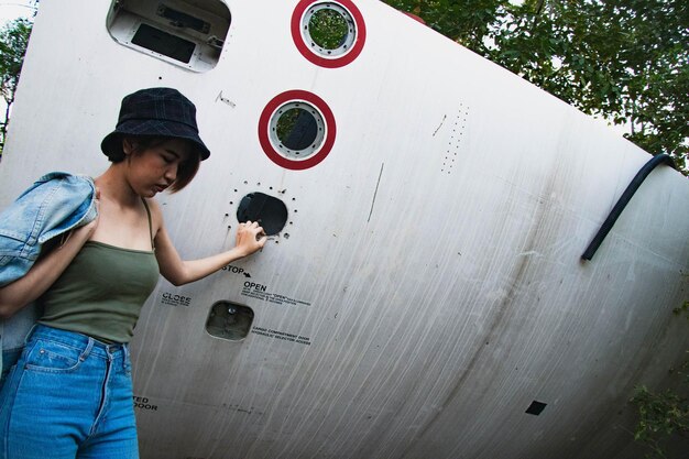 Young woman looking away standing against metal structure