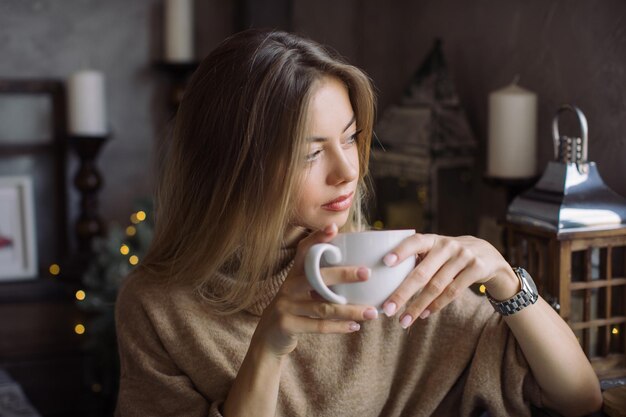 写真 コーヒーカップを握っている若い女性が目をそらしている