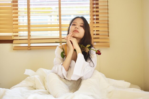 Young woman looking away while sitting on bed at home