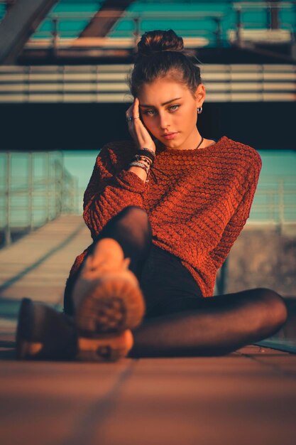 Young woman looking away while sitting on floor