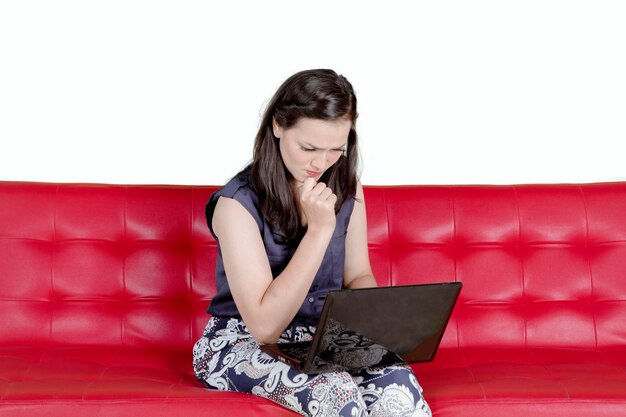 Young woman looking away while sitting on sofa