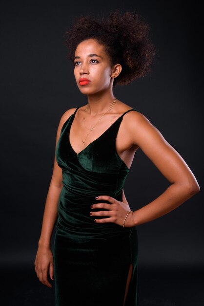 Young woman looking away while standing against black background