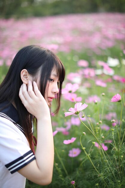 写真 花をかせている植物に立っている若い女性が目をそらしている