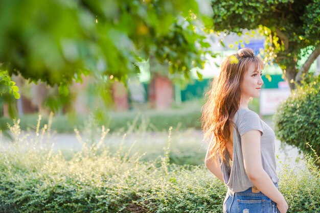 Foto giovane donna che guarda da un'altra parte mentre si trova contro le piante