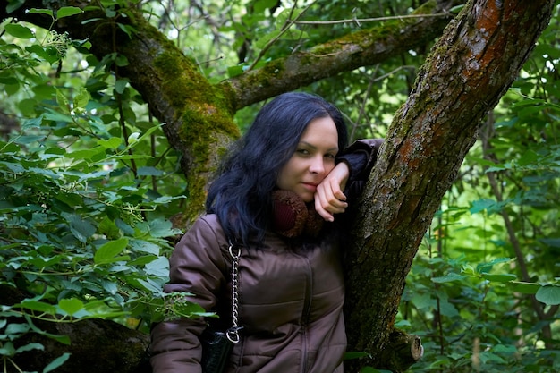 Photo young woman looking away while standing against tree