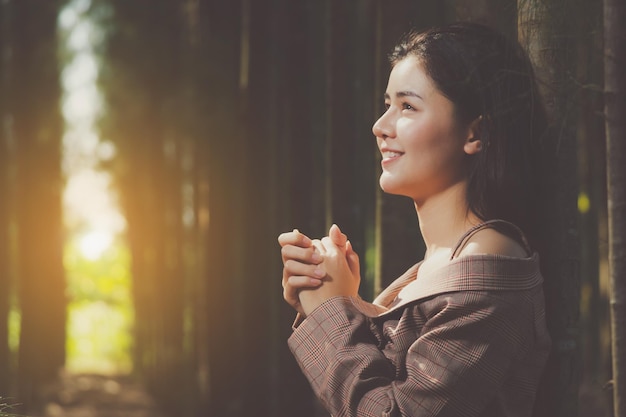 Photo young woman looking away while standing against trees