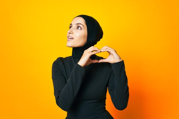 Young woman looking away while standing against yellow background