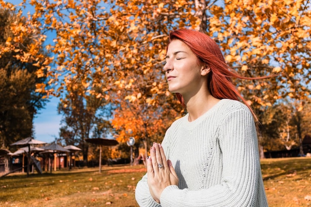 Foto giovane donna che guarda lontano mentre si trova accanto a un albero durante l'autunno