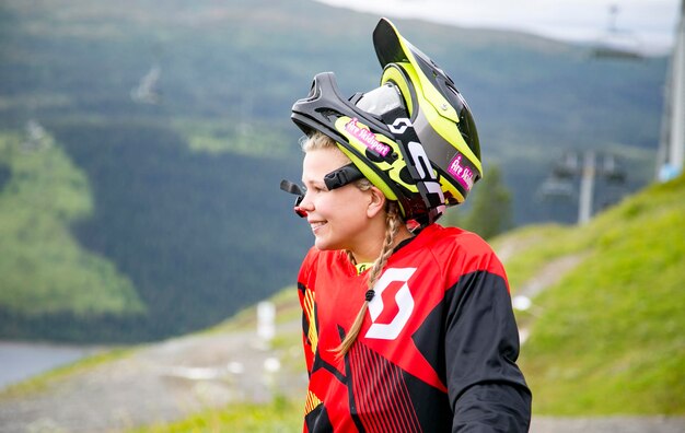 Foto giovane donna che guarda lontano mentre indossa un casco contro la montagna