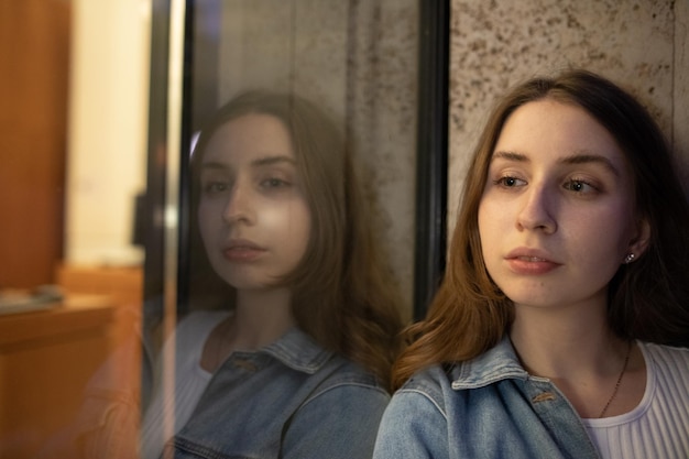 Photo young woman looking away with reflection on glass window