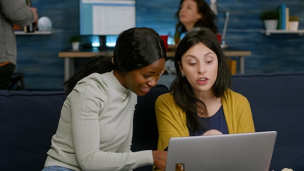 Photo young woman looking at camera while sitting on laptop