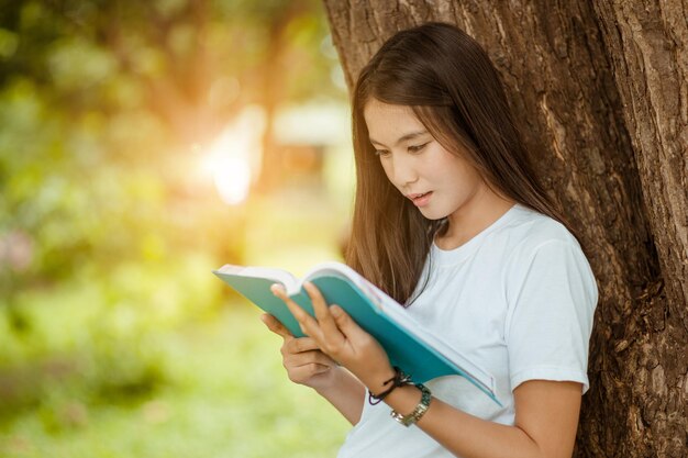 Young woman looking at camera while sitting on tree trunk