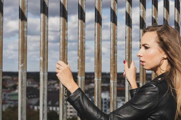 Foto giovane donna che guarda il paesaggio cittadino mentre si trova accanto alla recinzione