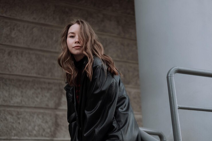 Photo 壁の向かいにある階段に座っている若い女性が下を見ている