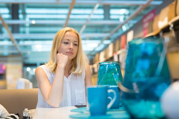 Photo young woman looking down while sitting on table