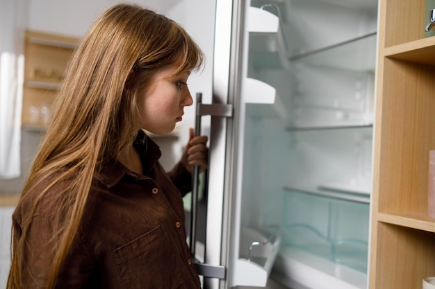 Photo young woman looking in empty refrigerator