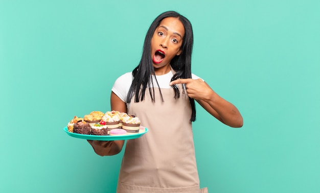 Young woman looking excited and surprised pointing to the side and upwards to copy space