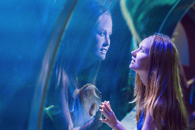 Young woman looking at fish in a tunnel aquarium.