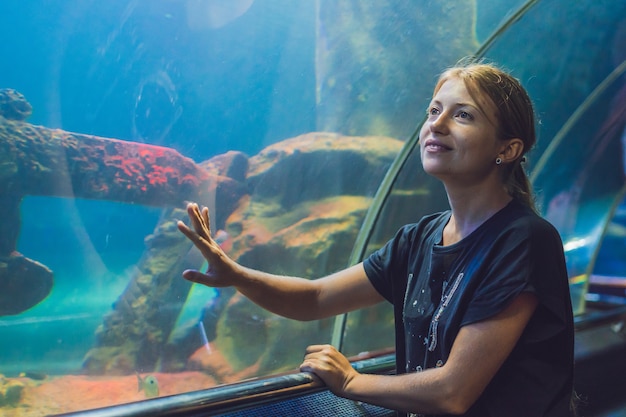 トンネル水族館で魚を見ている若い女性。