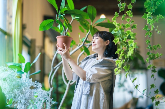 Photo a young woman looking at the foliage plants with a smile