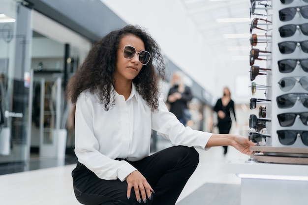 Foto giovane donna che guarda gli occhiali sul bancone del reparto di optometria