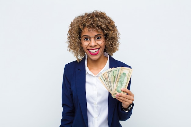 Young woman looking happy and pleasantly surprised, excited with a fascinated and shocked expression with euro banknotes