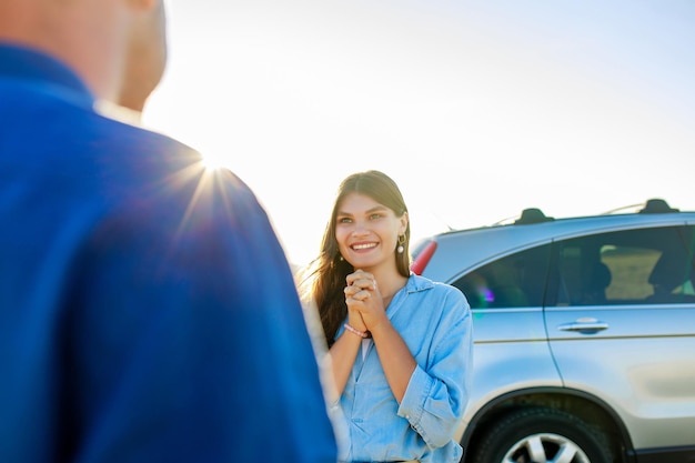 車の近くで愛に満ちた彼氏の目を見つめる若い女性