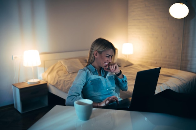 Young woman looking at her computer in a bedroom