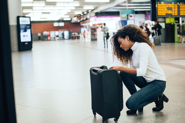 Young woman looking at her luggage at airport.